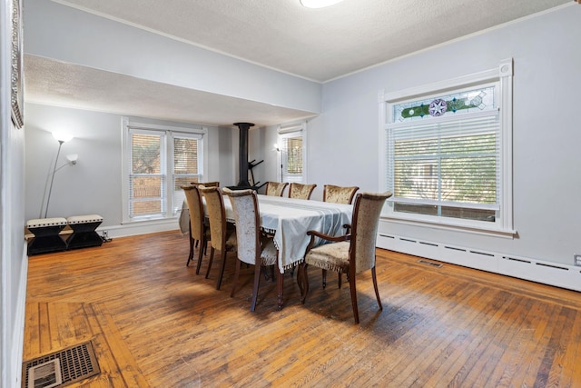 dining space featuring a wood stove, a textured ceiling, plenty of natural light, and hardwood / wood-style floors