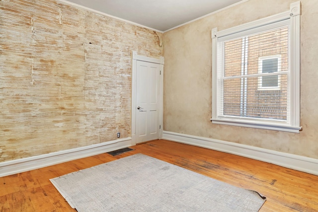 unfurnished room with ornamental molding, plenty of natural light, and hardwood / wood-style floors