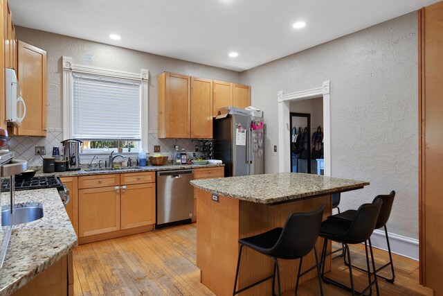 3017 James Ave S, Minneapolis, MN 55408 - kitchen featuring stainless steel appliances, a textured wall, tasteful backsplash, a kitchen breakfast bar, and a kitchen island