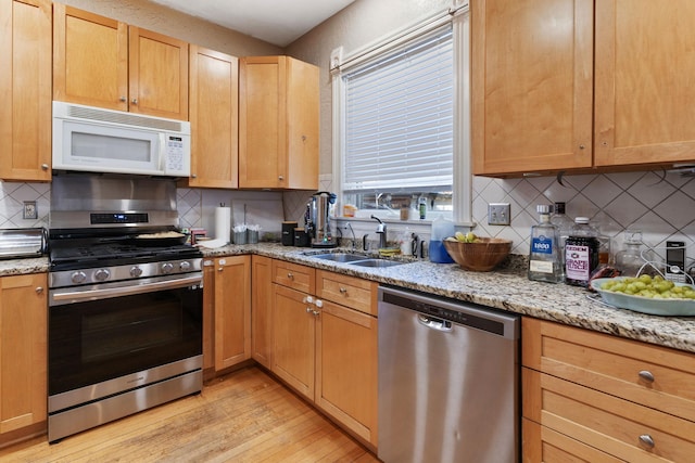 3017 James Ave S, Minneapolis, MN 55408 - kitchen with appliances with stainless steel finishes, light wood-type flooring, backsplash, and light stone countertops