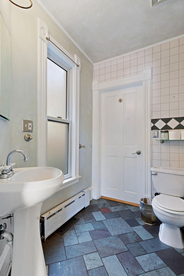 bathroom featuring tile walls, toilet, and a baseboard radiator