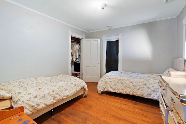 bedroom with ornamental molding, wood-type flooring, and a closet