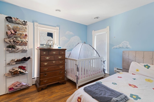 bedroom featuring baseboard heating and dark hardwood / wood-style flooring