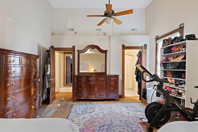 exercise room with ceiling fan, light wood-type flooring, and high vaulted ceiling