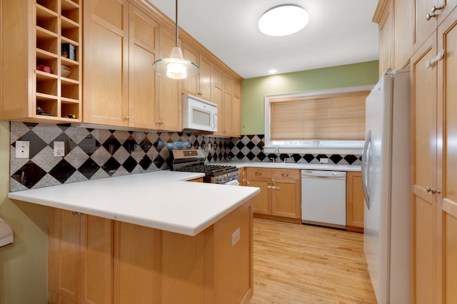 kitchen featuring light hardwood / wood-style floors, kitchen peninsula, white appliances, backsplash, and decorative light fixtures