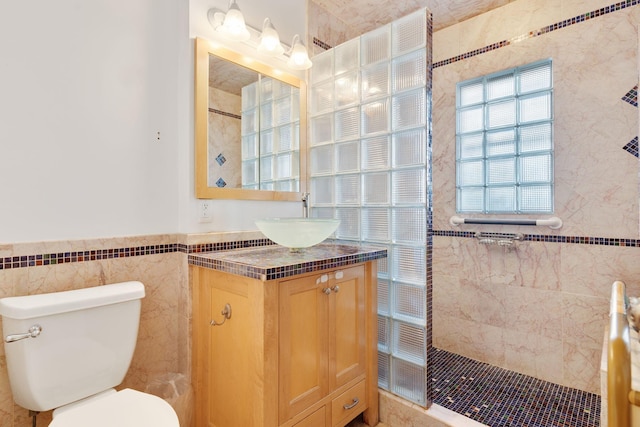 bathroom with walk in shower, vanity, tile walls, and toilet