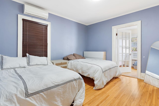 bedroom featuring light wood-type flooring, crown molding, and an AC wall unit