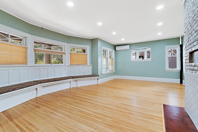 interior space with light hardwood / wood-style floors, crown molding, and a wall mounted air conditioner