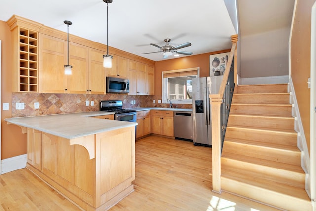 kitchen featuring pendant lighting, kitchen peninsula, light hardwood / wood-style flooring, stainless steel appliances, and light brown cabinetry