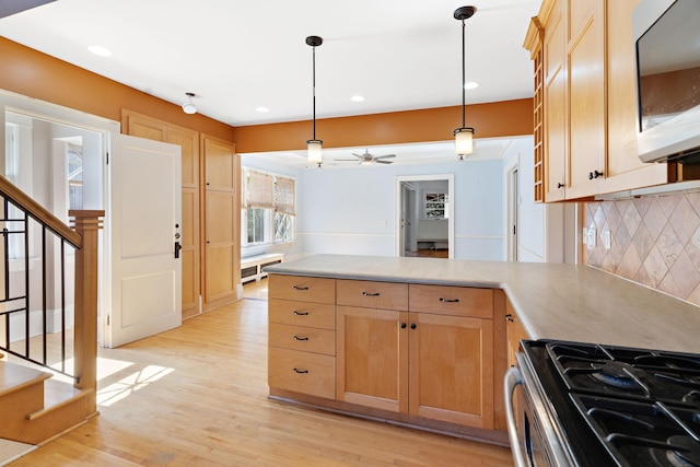 kitchen with stainless steel range with gas stovetop, light hardwood / wood-style flooring, decorative backsplash, decorative light fixtures, and ceiling fan