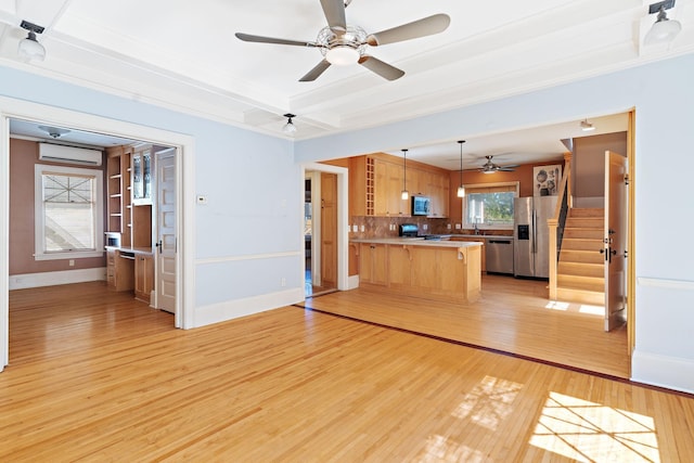 kitchen featuring ceiling fan, hanging light fixtures, kitchen peninsula, stainless steel appliances, and light wood-type flooring