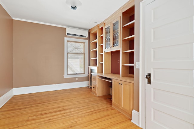 unfurnished office featuring built in desk, crown molding, a wall mounted AC, and light hardwood / wood-style flooring