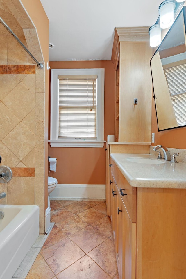 full bathroom with tile patterned flooring, tiled shower / bath, vanity, and toilet