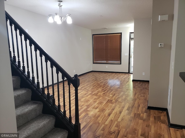 stairs featuring wood-type flooring, a textured ceiling, and a chandelier