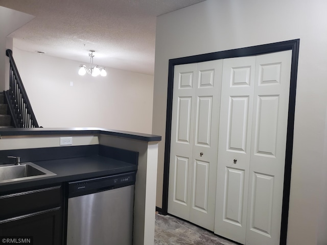 kitchen with a textured ceiling, stainless steel dishwasher, sink, and a notable chandelier