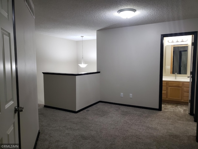 carpeted spare room featuring a textured ceiling and sink