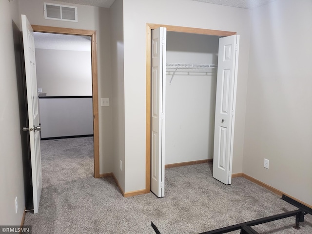 unfurnished bedroom with light carpet, a textured ceiling, and a closet