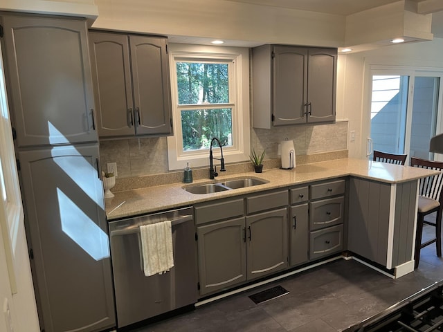 kitchen featuring sink, kitchen peninsula, stainless steel dishwasher, backsplash, and gray cabinetry