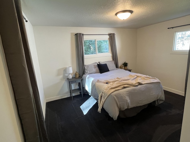 bedroom featuring a textured ceiling, multiple windows, and dark carpet