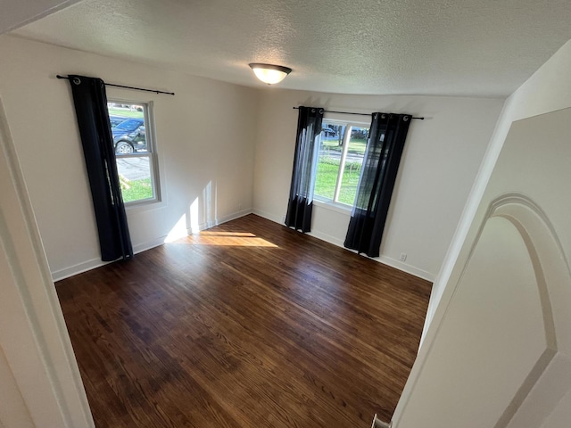 empty room with a textured ceiling and dark hardwood / wood-style flooring