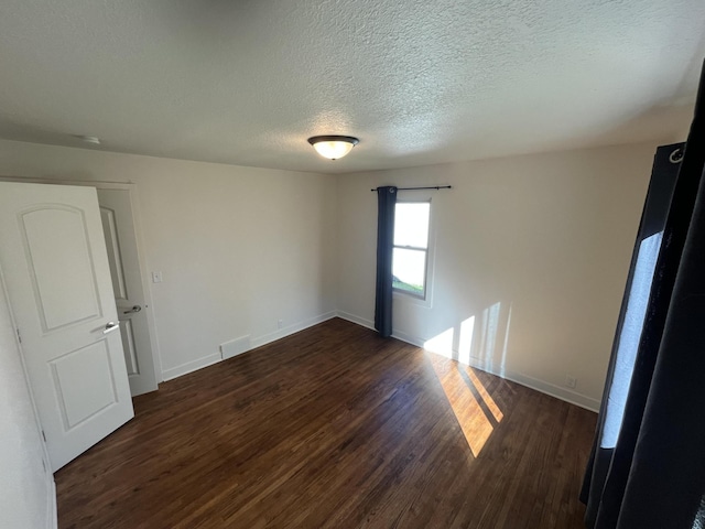 unfurnished room featuring a textured ceiling and dark hardwood / wood-style floors