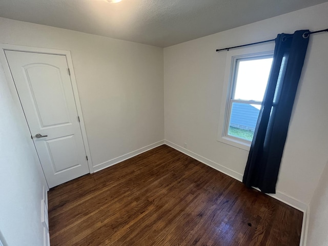 unfurnished room featuring a healthy amount of sunlight and dark hardwood / wood-style floors