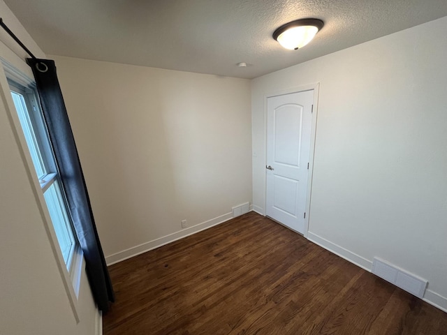 empty room featuring dark hardwood / wood-style flooring and a textured ceiling