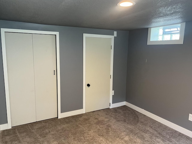 unfurnished bedroom featuring a textured ceiling and dark colored carpet