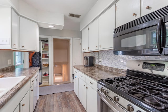 kitchen with gas stove, backsplash, light hardwood / wood-style floors, and white cabinets