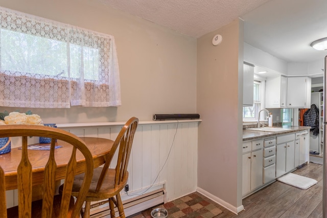 dining space featuring a textured ceiling, a baseboard radiator, sink, and dark hardwood / wood-style flooring