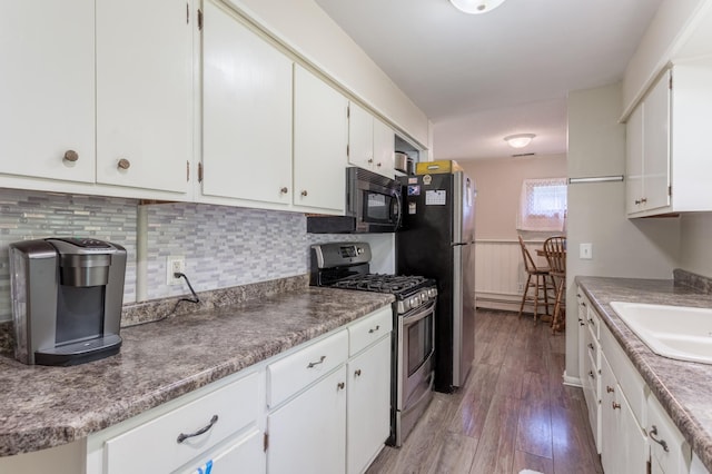 kitchen with dark hardwood / wood-style flooring, sink, stainless steel appliances, a baseboard heating unit, and white cabinetry