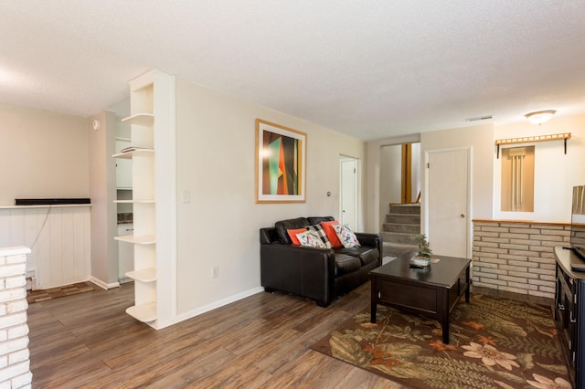 living room with built in shelves, dark hardwood / wood-style flooring, and a textured ceiling