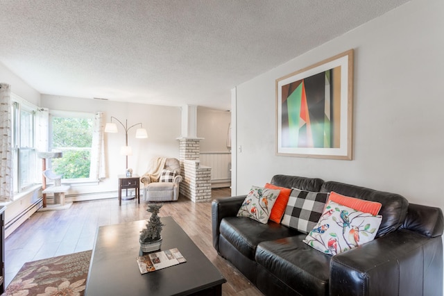 living room with wood-type flooring, a baseboard heating unit, and a textured ceiling