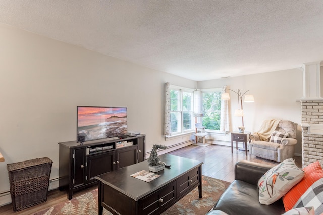 living room with a baseboard heating unit, light hardwood / wood-style flooring, and a textured ceiling