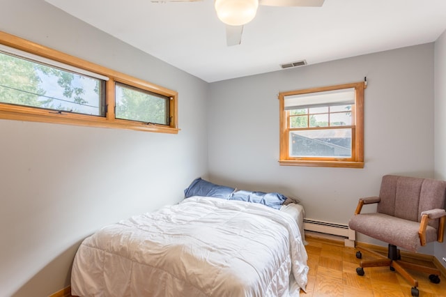 bedroom with parquet flooring, a baseboard heating unit, and ceiling fan