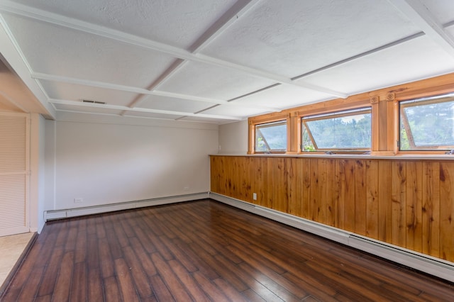 empty room featuring baseboard heating, hardwood / wood-style floors, a wealth of natural light, and a textured ceiling