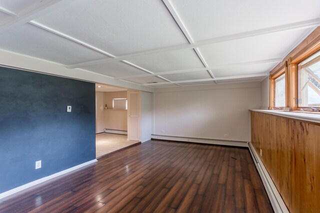 empty room featuring coffered ceiling, hardwood / wood-style floors, and a baseboard heating unit