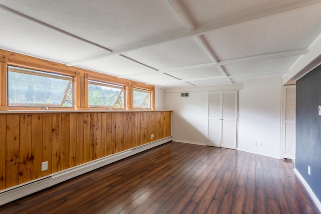 interior space featuring beamed ceiling, dark hardwood / wood-style floors, a baseboard heating unit, wood walls, and a textured ceiling