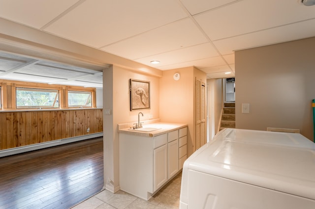 laundry area with washer / clothes dryer, light hardwood / wood-style flooring, sink, and a baseboard heating unit