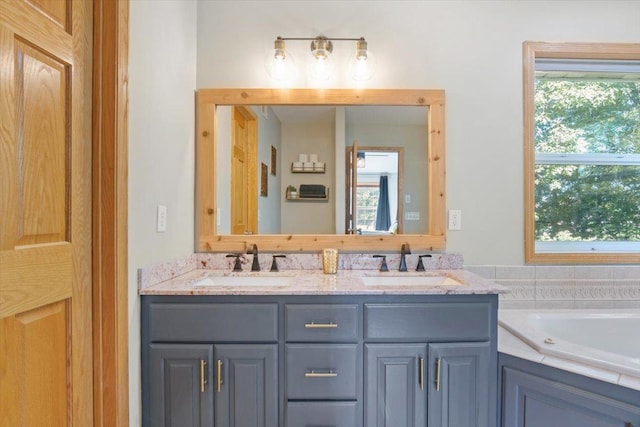 bathroom with vanity, a tub to relax in, and a healthy amount of sunlight