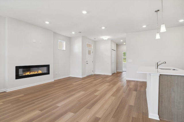 unfurnished living room featuring sink and light hardwood / wood-style flooring