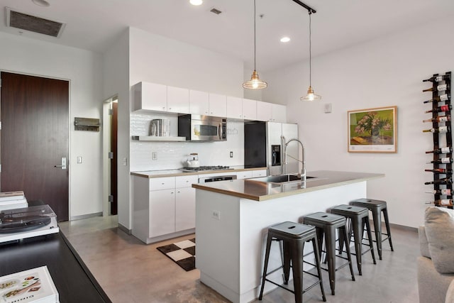 kitchen with stainless steel appliances, a kitchen bar, hanging light fixtures, and white cabinets