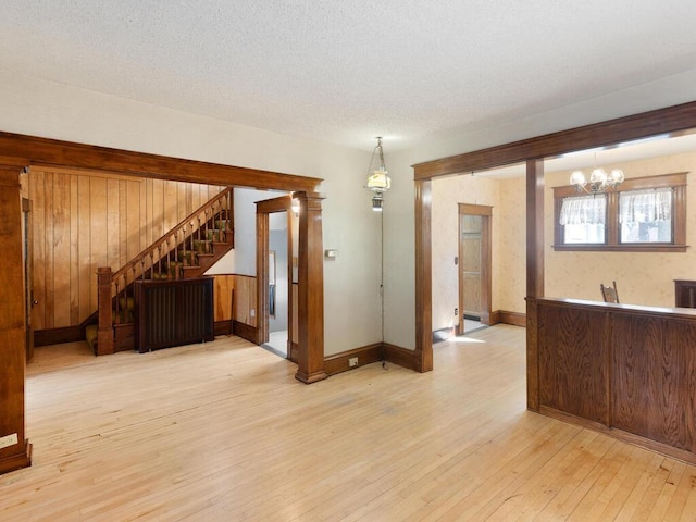 interior space featuring a textured ceiling, light wood-type flooring, and an inviting chandelier