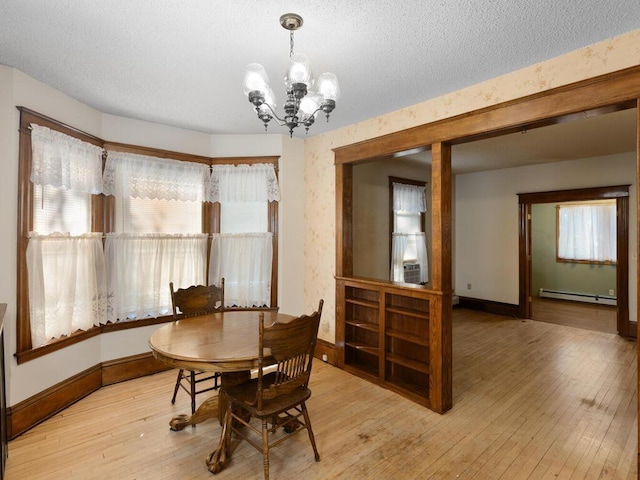 dining space featuring baseboard heating, a textured ceiling, cooling unit, an inviting chandelier, and light hardwood / wood-style flooring