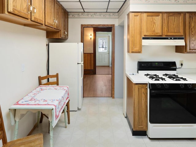 kitchen with a drop ceiling, white refrigerator, and gas stove