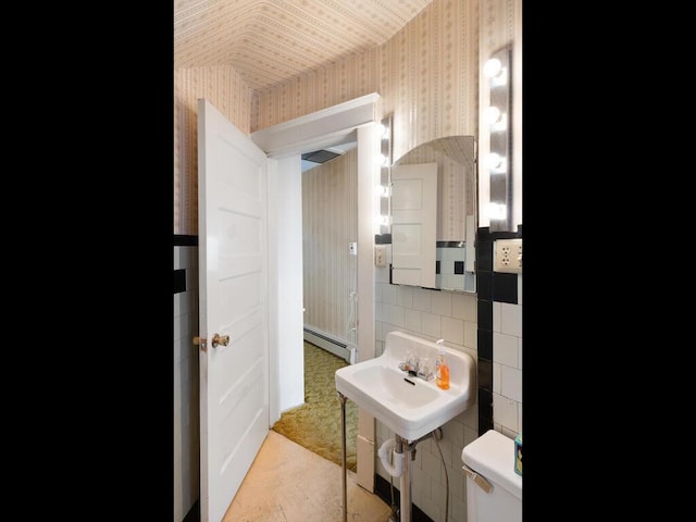 bathroom featuring baseboard heating, toilet, and tasteful backsplash