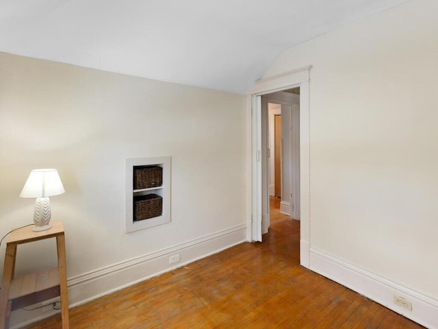 spare room featuring lofted ceiling and hardwood / wood-style flooring