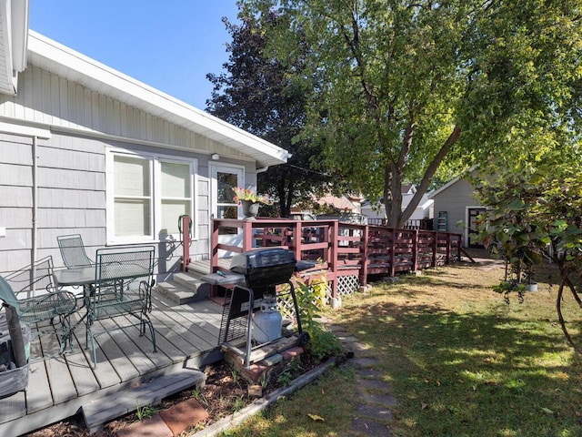 wooden terrace featuring area for grilling and a yard