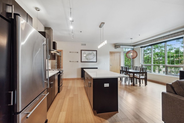 kitchen featuring a kitchen island, decorative light fixtures, track lighting, appliances with stainless steel finishes, and light hardwood / wood-style floors