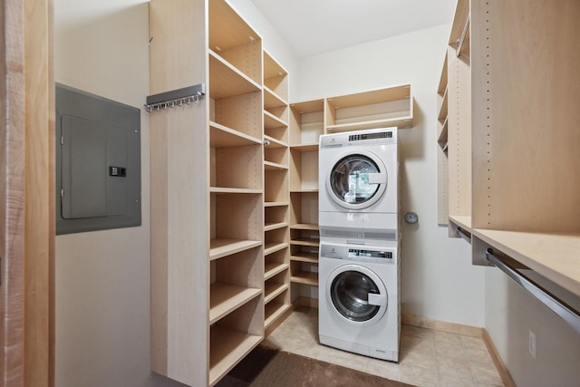 clothes washing area with light tile patterned floors, electric panel, and stacked washer / drying machine